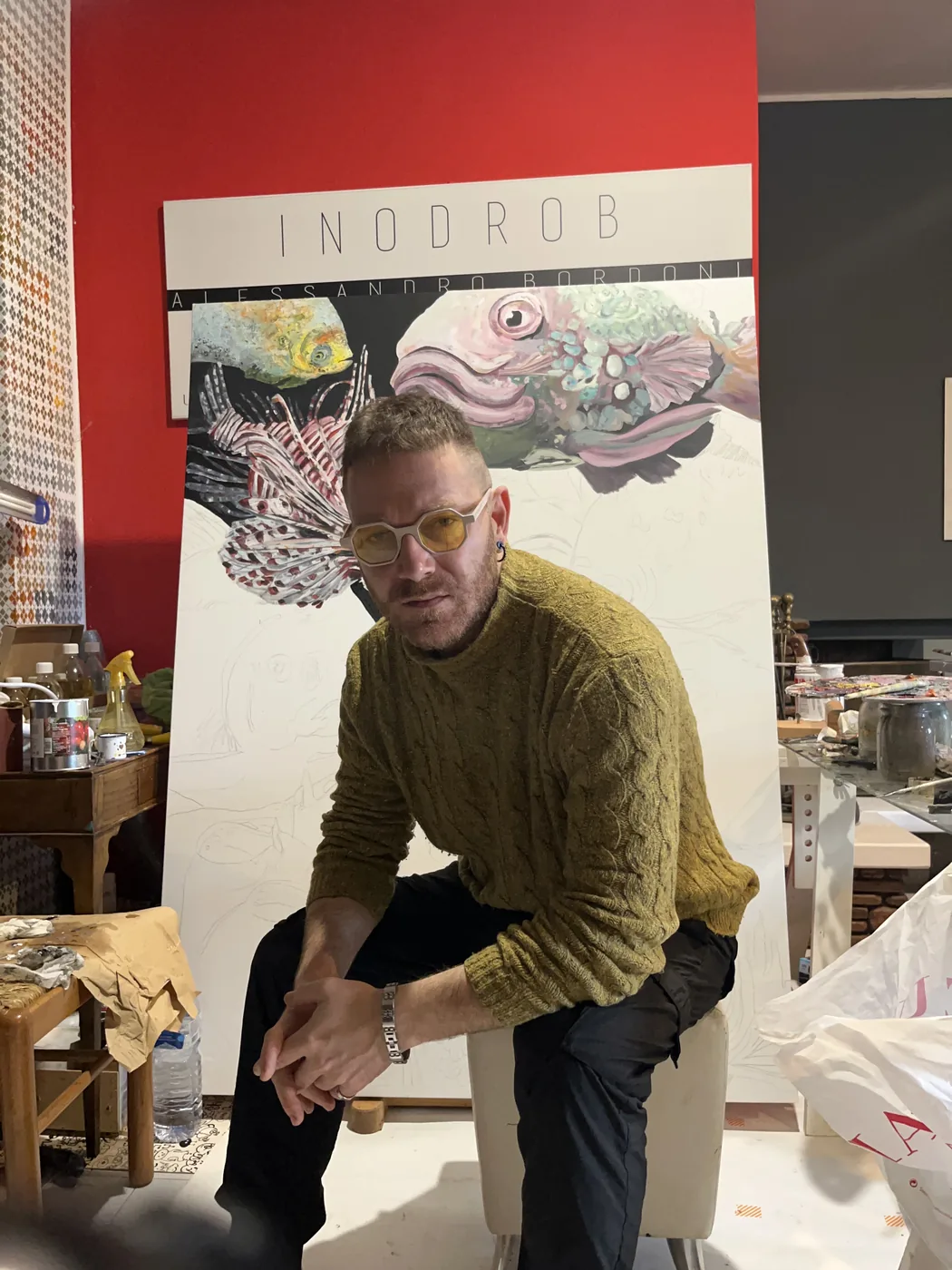 Alessandro Bordoni seduto davanti a una tela in lavorazione, nel suo atelier.